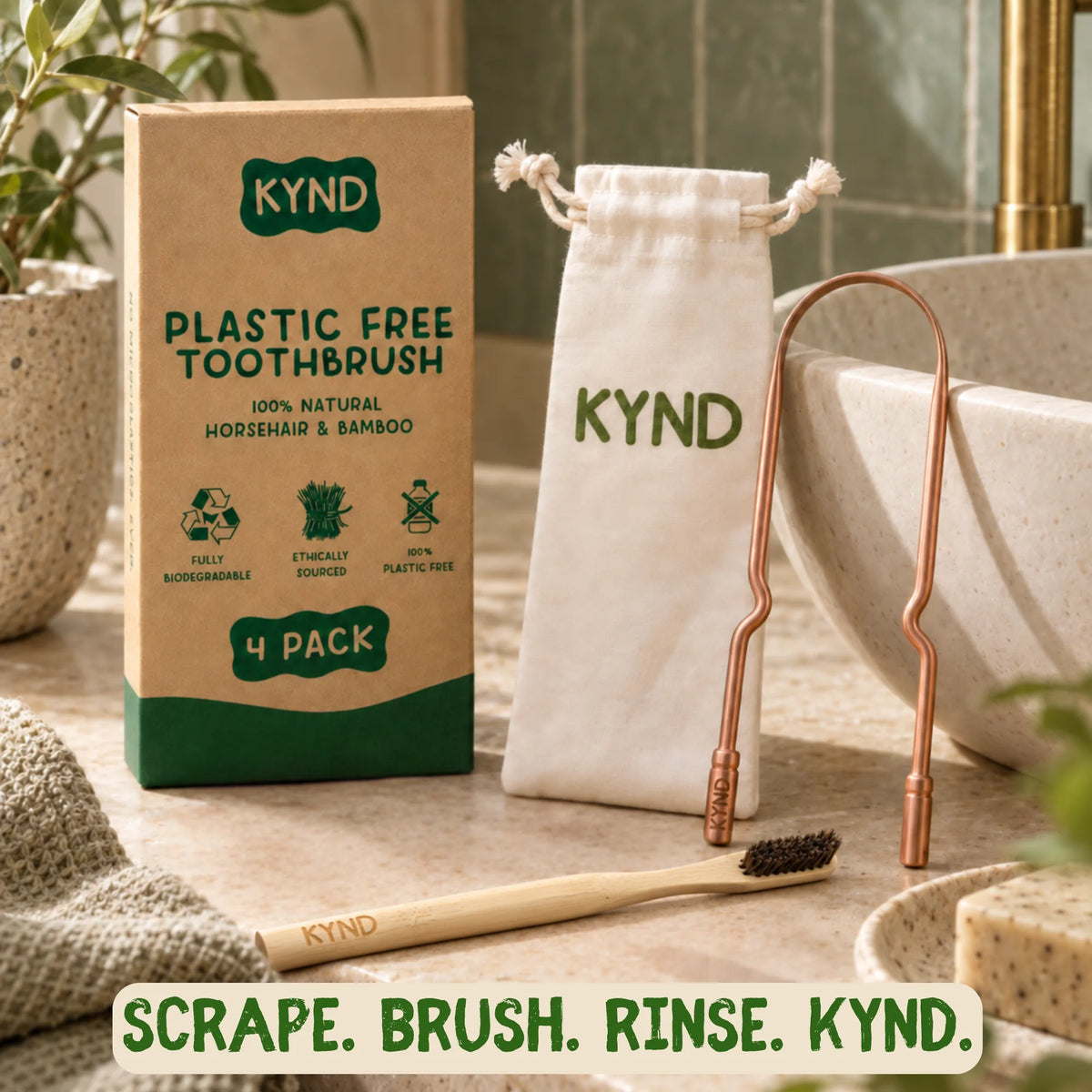 KYND plastic-free toothbrush 4-pack shown with its kraft paper packaging box, a white drawstring pouch, a copper tongue scraper, and a bamboo and horsehair toothbrush on a bathroom counter.