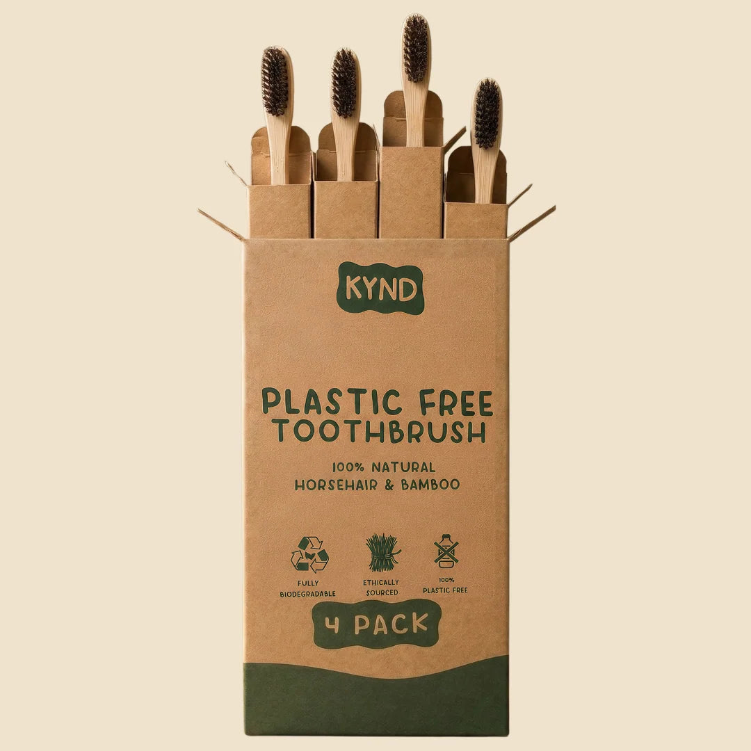 Kraft paper packaging of KYND plastic-free toothbrushes with four brushes inside on a beige background.