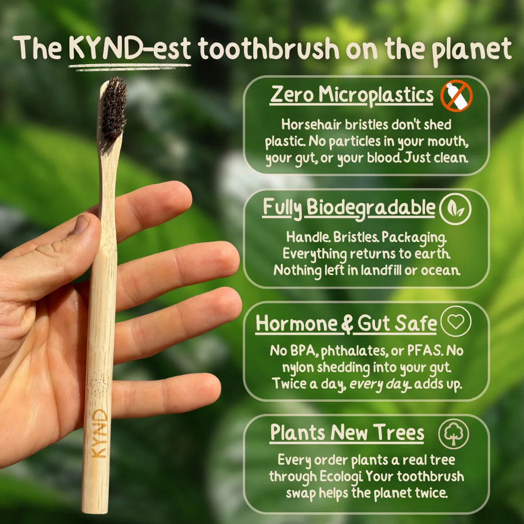 KYND horsehair and bamboo toothbrush held by a hand with green leafy background and KYND branding.